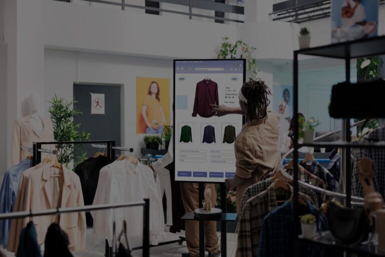 A person browsing clothing options on a digital touchscreen in a retail store.